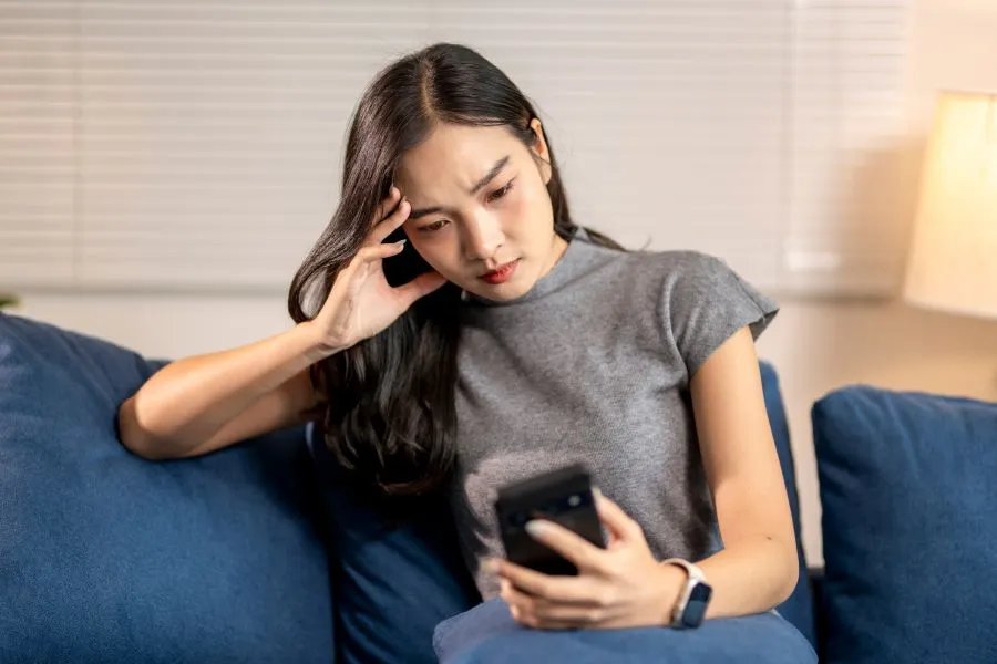 A woman looking at her phone confused.