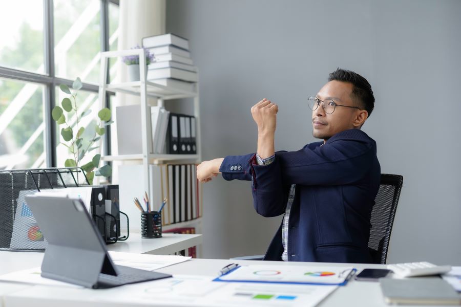 Man stretching behind his desk