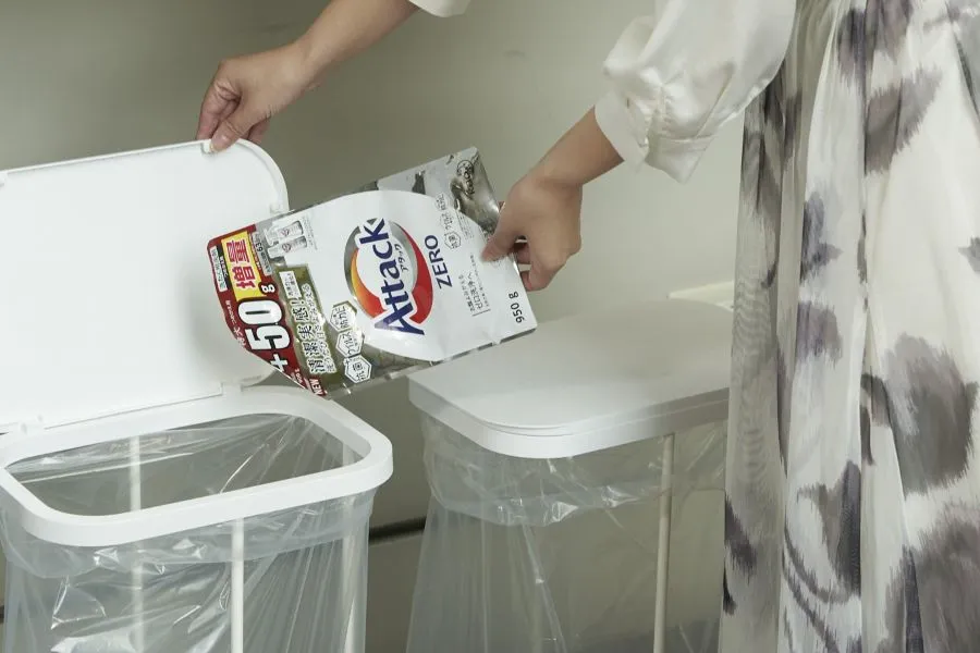 A person putting a package into a trash can.