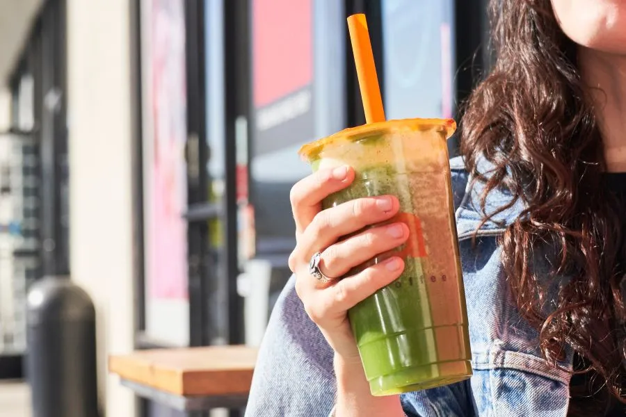 A person holding a cup of drink with a straw.