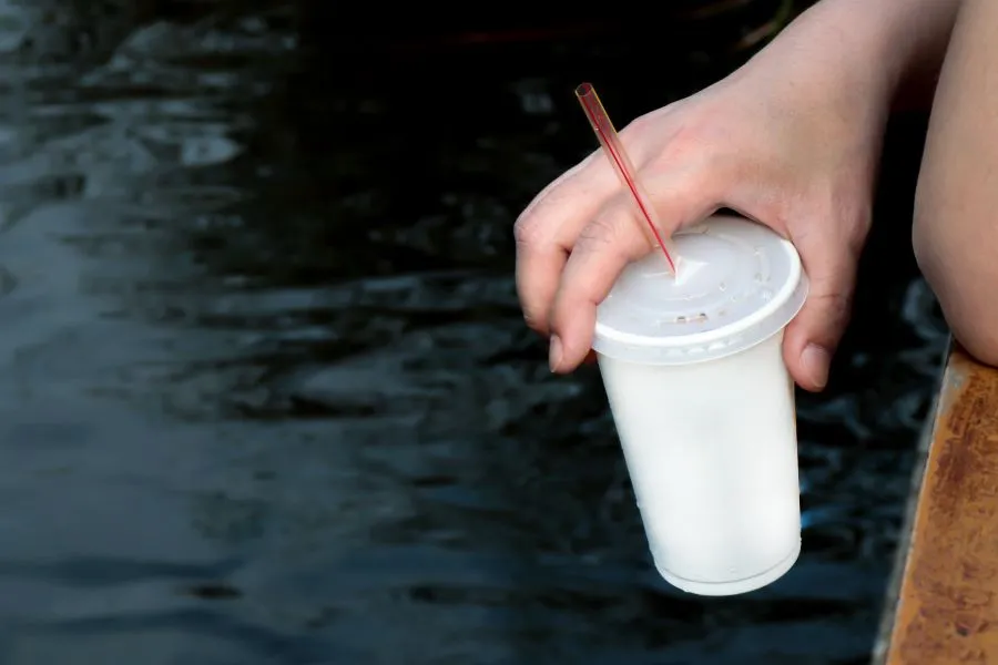 A hand holding a straw and a cup.