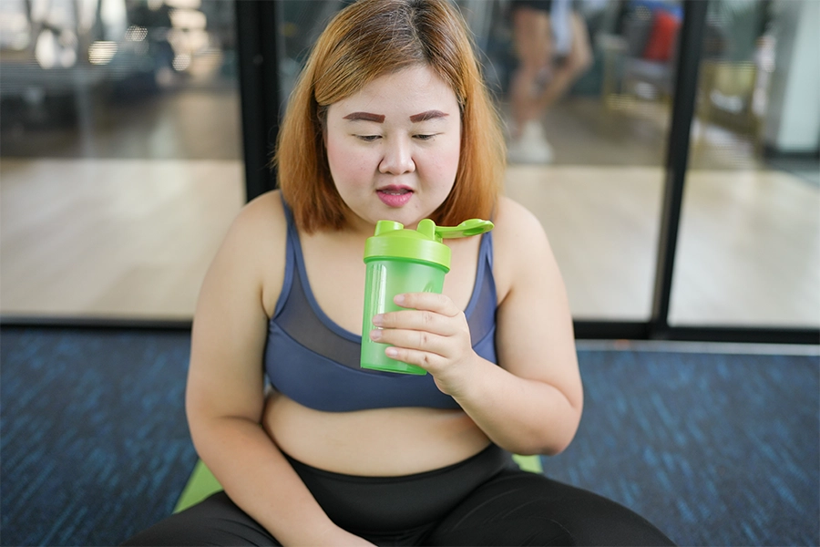 Overweight Asian woman drinking protein shake.