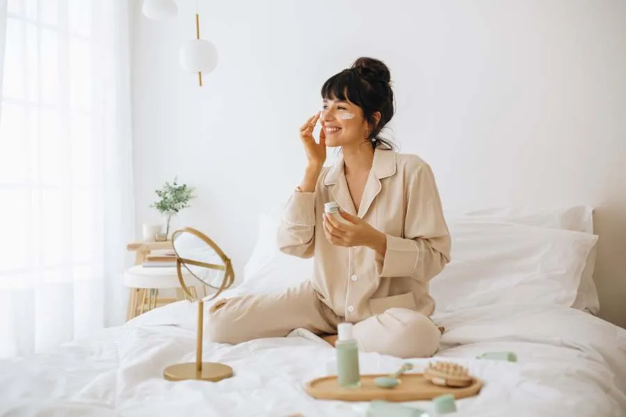 woman sitting on bed using skin care
