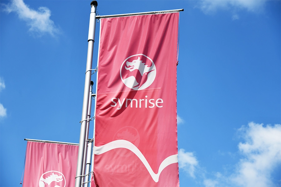 Branded Symrise flags against blue sky.